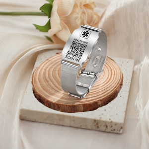 May include: A silver metal bracelet with a medical symbol and a QR code that says "HEALTH INFO" and "SCAN ME".
