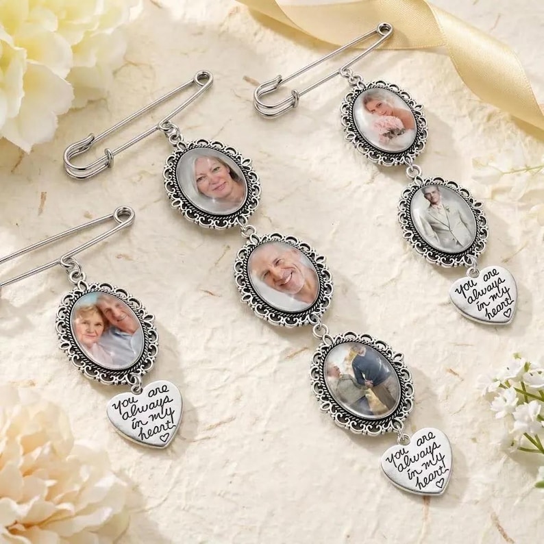 Puede incluir: Tres broches de metal plateado, cada uno con marcos ovalados que contienen retratos fotogr&aacute;ficos. Los broches incluyen dijes en forma de coraz&oacute;n grabados con el texto "you are always in my heart" con un peque&ntilde;o s&iacute;mbolo de coraz&oacute;n.