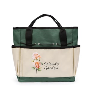 May include: A gardening tote bag with a green top and black handles. The front of the bag is beige with a watercolor image of roses and the text "Selena's Garden". The bag has multiple pockets and a drawstring closure.