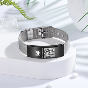Peut inclure: Un bracelet en métal argenté avec un bandeau noir qui dit "HEALTH INFO" et "SCAN ME" avec un symbole médical et un code QR.