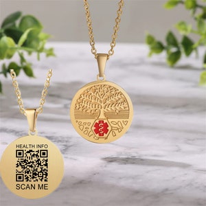 Peut inclure: Collier pendentif doré. Un pendentif présente un motif d'arbre avec un symbole médical rouge. L'autre pendentif porte un code QR avec le texte "HEALTH INFO" et "SCAN ME".