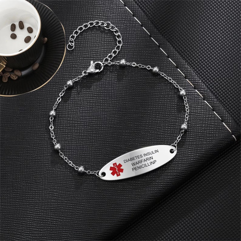 May include: A silver medical alert bracelet with a red medical symbol and the text "DIABETES INSULIN WARFARIN PENICILLIN".