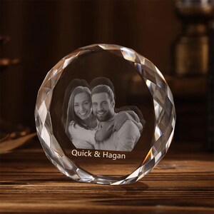 May include: A crystal paperweight with a 3D engraved image of a couple. The paperweight is clear and has a diamond-shaped design. The text "Quick & Hagan" is engraved on the bottom of the paperweight.