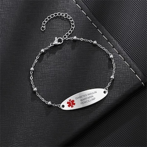 May include: A silver medical alert bracelet with a red star of life symbol and the text "DIABETES INSULIN WARFARIN PENICILLIN".