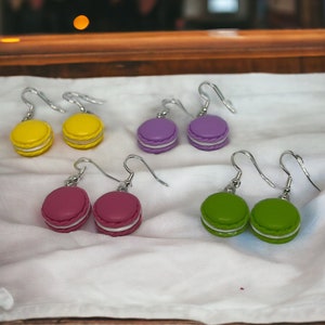 Könnte beinhalten: Ein Set mit sechs Ohrringen in Macaron-Form in Gelb, Lila, Rosa und Grün. Die Ohrringe sind aus Polymer Clay gefertigt und haben silberne Haken.