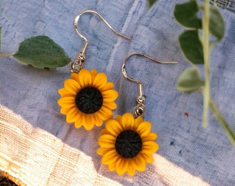 May include: A pair of sunflower earrings with gold hooks. The sunflowers are yellow with black centers.