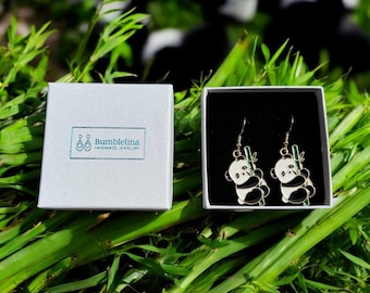 Könnte beinhalten: Ein Paar Hängeohrringe mit einem schwarz-weißen Pandabären, der einen grünen Bambusstab hält. Die Ohrringe befinden sich in einer weißen Schachtel mit dem Text "Bumblelina Handmade Jewellery".