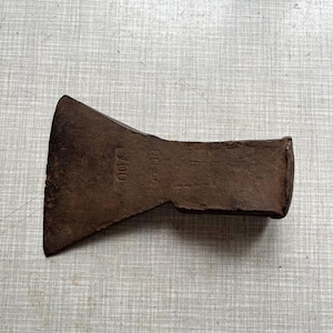Puede incluir: Una cabeza de hacha oxidada y vintage, con una hoja ancha y un ojo rectangular para el mango. El metal está muy desgastado, mostrando signos de edad y uso. El número "100" está estampado en el lateral.