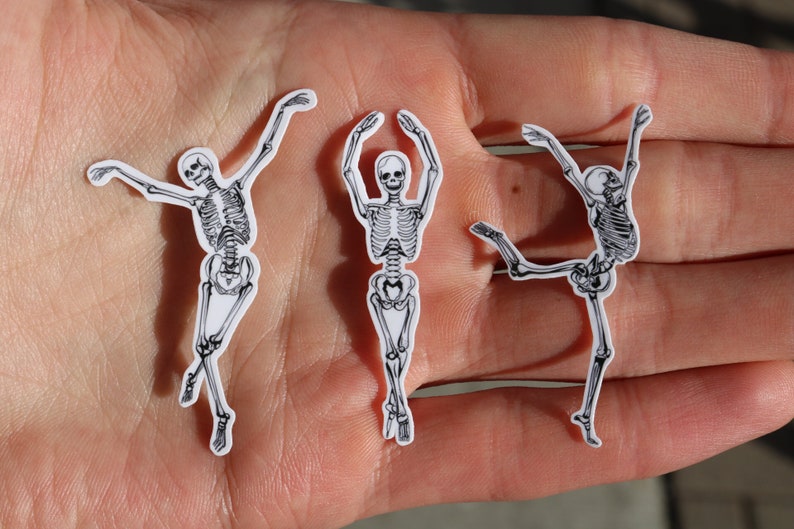 Op de afbeelding: Drie zwart-witte skelet stickers op een hand. De skeletten staan in verschillende poses, &eacute;&eacute;n staat met de armen omhoog, &eacute;&eacute;n staat met de armen gespreid en &eacute;&eacute;n staat met &eacute;&eacute;n been omhoog.