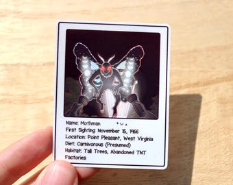 Könnte beinhalten: Ein weißer Aufkleber mit einer Mothman-Illustration vor schwarzem Hintergrund. Der Mothman hat rote Augen und große Flügel mit einem Halbmond-Design. Der Text auf dem Aufkleber enthält den Namen, das Sichtungsdatum, den Ort, die Ernährung und den Lebensraum.