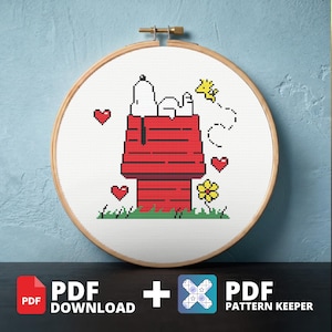 Puede incluir: Un patrón de punto de cruz con Snoopy en su caseta roja, con Woodstock y corazones. El diseño está en un bastidor de bordado de madera. También se ven las palabras "PDF DOWNLOAD" y "PDF PATTERN KEEPER".