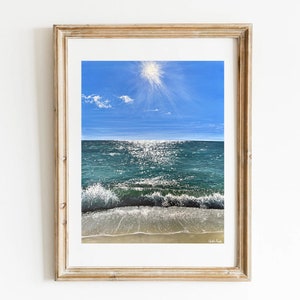 May include: A framed painting of a seascape with a bright blue sky, a sun shining down, and a turquoise ocean with white waves crashing on the shore.