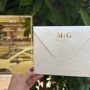 Invito di nozze di lusso in plexiglass specchiato color oro. Busta perlescente color avorio, busta stampata in lamina d'oro personalizzata.