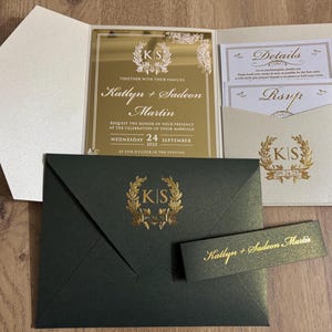 Ensemble d'invitations de mariage de luxe. Miroir en plexiglas doré. Poche et ceinture. Faire-part de mariage de luxe vert et ivoire préparé avec du papier pailleté.