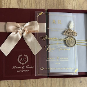 Invito di nozze in acrilico con lussuosa scatola bordeaux. Invito in scatola con nastro e stampa olografica. Acrilico con busta in pergamena.