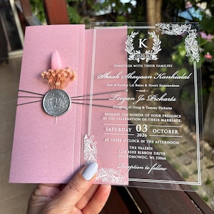 Invito a nozze a mezza busta rosa perlato. Acrilico trasparente con stampa a lamina bianca. Sigillo di ceralacca argentata, filo argentato. Fiori secchi.