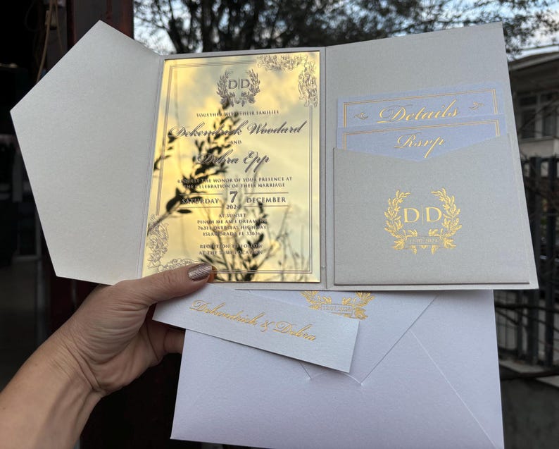 May include: A white and gold wedding invitation with a pocket for a RSVP card. The invitation features a gold floral design and the text "Dokeylog Woodard and Sierra Epp" with the date "7 December 2023".