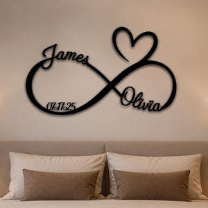 Peut inclure: Une enseigne murale noire représentant un symbole infini entrelacé avec une forme de cœur. L'enseigne inclut les prénoms James et Olivia en écriture cursive, ainsi que la date 07.17.25 intégrée dans le design de la boucle de l'infini.