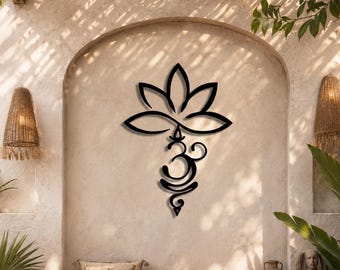 Op de afbeelding: Een zwart metalen wanddecoratie met een gestileerd lotusbloemontwerp dat direct boven een Om-symbool is geplaatst. Het decoratieve object heeft een gladde, matte afwerking en is centraal bevestigd op een lichtgekleurde, getextureerde muur.