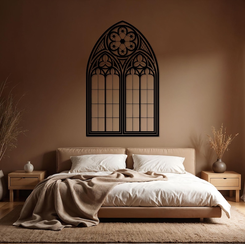May include: Black, gothic-style window wall art. The decorative piece features an arched top with a floral design and two rectangular window panels. The artwork is mounted on a brown wall above a bed with white bedding.
