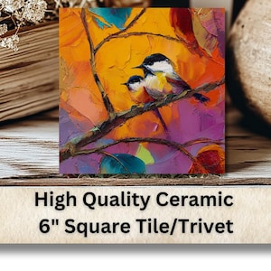 May include: A 6-inch square ceramic tile/trivet featuring an impressionistic painting of two birds perched on a branch. The artwork uses vibrant colors, including orange, purple, and blue. The tile is displayed with a stack of books and a decorative vase.