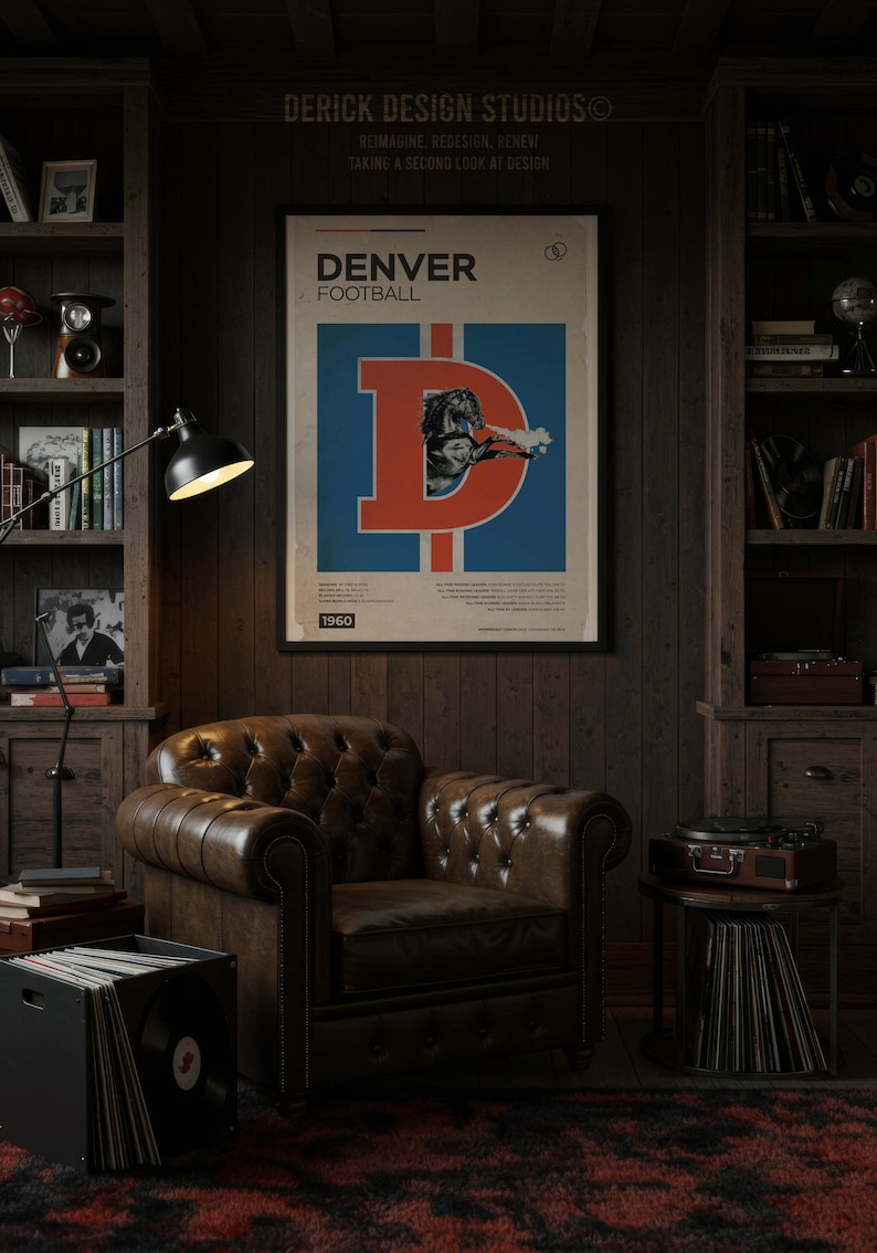 May include: A vintage-style poster with the text "DENVER FOOTBALL" and a large "D" logo in red and blue. The poster is framed and hangs above a brown leather armchair in a room with wooden paneling and bookshelves. The year "1960" is at the bottom.