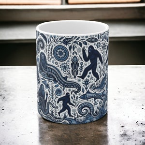 Cryptid woods in blue 11oz mug with mothman, bigfoot, the jersey devil, jackalope, and the frogman of loveland