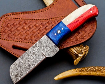 May include: A handmade Damascus steel knife with a blue, white and red handle. The handle is designed to resemble the Texas flag. The knife is in a leather sheath.
