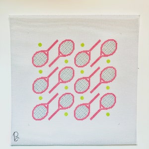 May include: A white canvas with a pink and gray tennis racket pattern. The rackets are arranged in a diagonal pattern with green tennis balls scattered throughout.
