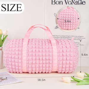 Op de afbeelding: Roze gewatteerde reistas met een bovenste handvat en twee banden. De tas is 46 cm lang en 24 cm hoog.