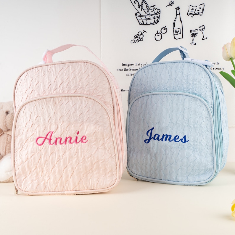 Pu&ograve; includere: Due zaini personalizzati per bambini, uno rosa con il nome "Annie" ricamato in rosa e l'altro azzurro chiaro con il nome "James" ricamato in blu.
