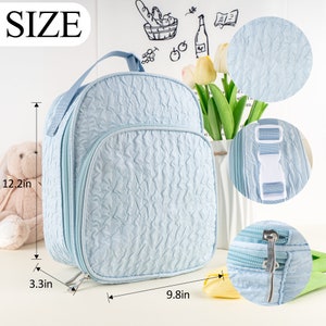 Pu&ograve; includere: Zaino imbottito di colore azzurro chiaro con chiusura a zip e spallacci regolabili. Lo zaino misura 31 cm di altezza, 25 cm di larghezza e 8,4 cm di profondit&agrave;.