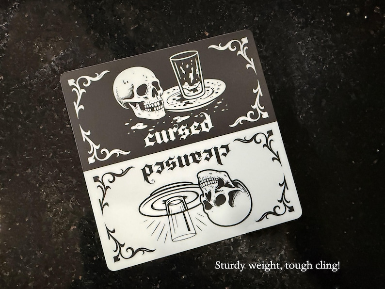 Sturdy magnet weight and tough dishwasher magnet cling! A black and white slim dishwasher magnet with a gothic theme. The top half features a skull, a glass, and the word 'cursed'. The bottom half shows a skull, a glass, and the word 'cleansed'. Ornate flourishes frame the design.