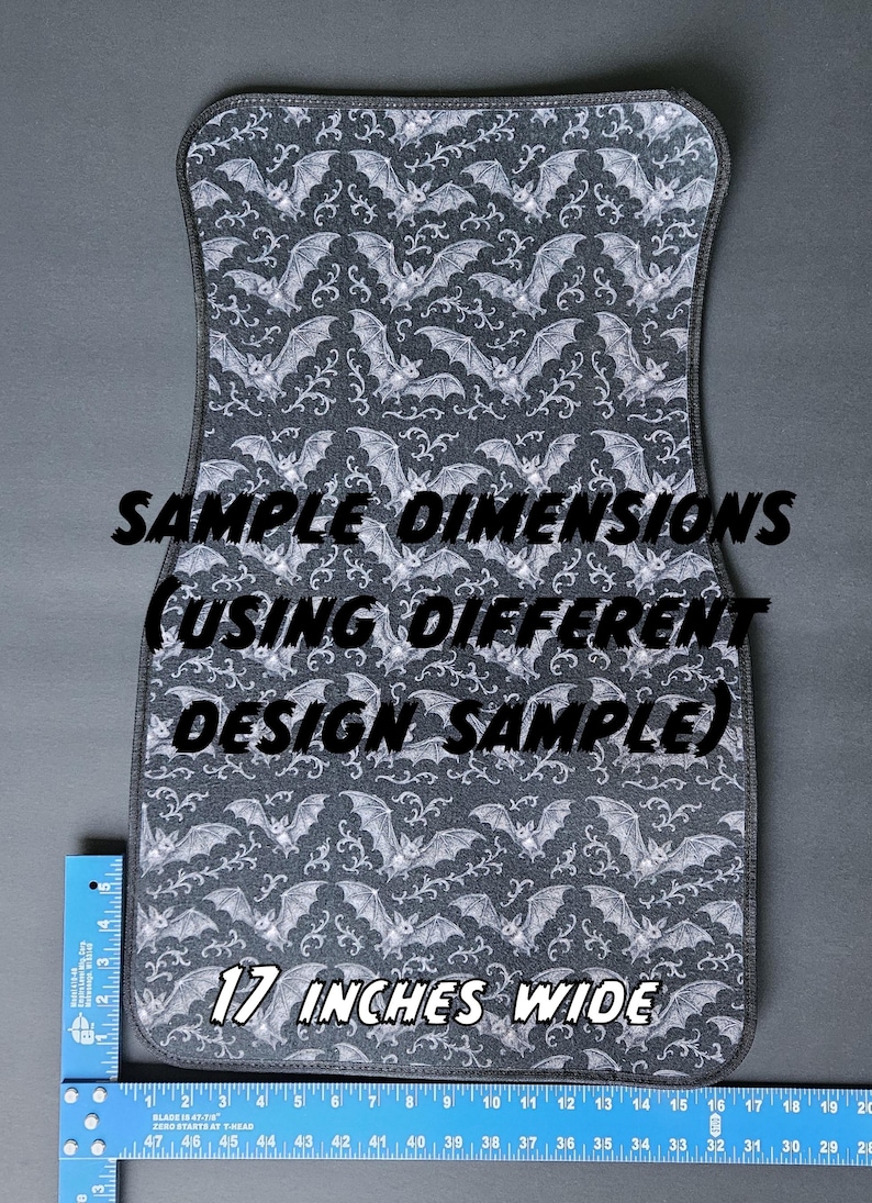 May include: A gray car floor mat with a repeating pattern of white bats and swirling designs. The mat is 17 inches wide and has the text "SAMPLE DIMENSIONS (USING DIFFERENT DESIGN SAMPLE)".