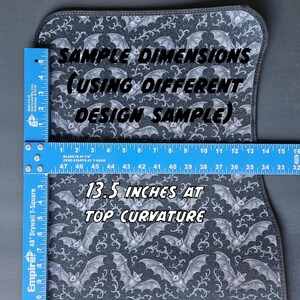 May include: A car floor mat with a bat and vine pattern in gray and white. The mat is measured with a ruler, showing a top curvature of 13.5 inches. Text on the mat reads "Sample Dimensions" and "13.5 inches at top curvature."