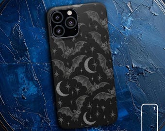 Può includere: Custodia per telefono nera con un motivo di pipistrelli, lune crescenti e stelle in grigio. I pipistrelli hanno ali dettagliate e uno stile vintage. La custodia è etichettata "SNAP CASE" in testo bianco.
