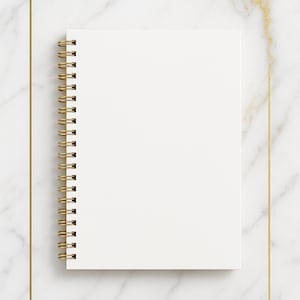 Puede incluir: Un cuaderno en espiral blanco en blanco con encuadernación en espiral dorada descansa sobre una superficie de mármol blanco. Un marco rectangular dorado rodea el cuaderno. El mármol tiene vetas doradas.