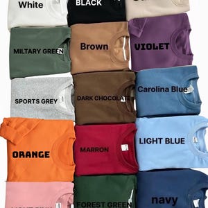May include: A collection of crewneck sweatshirts in various colors, including white, black, sand, military green, brown, violet, sports grey, dark chocolate, Carolina blue, orange, maroon, light blue, light pink, forest green, and navy. Each sweatshirt has the color name printed on it.