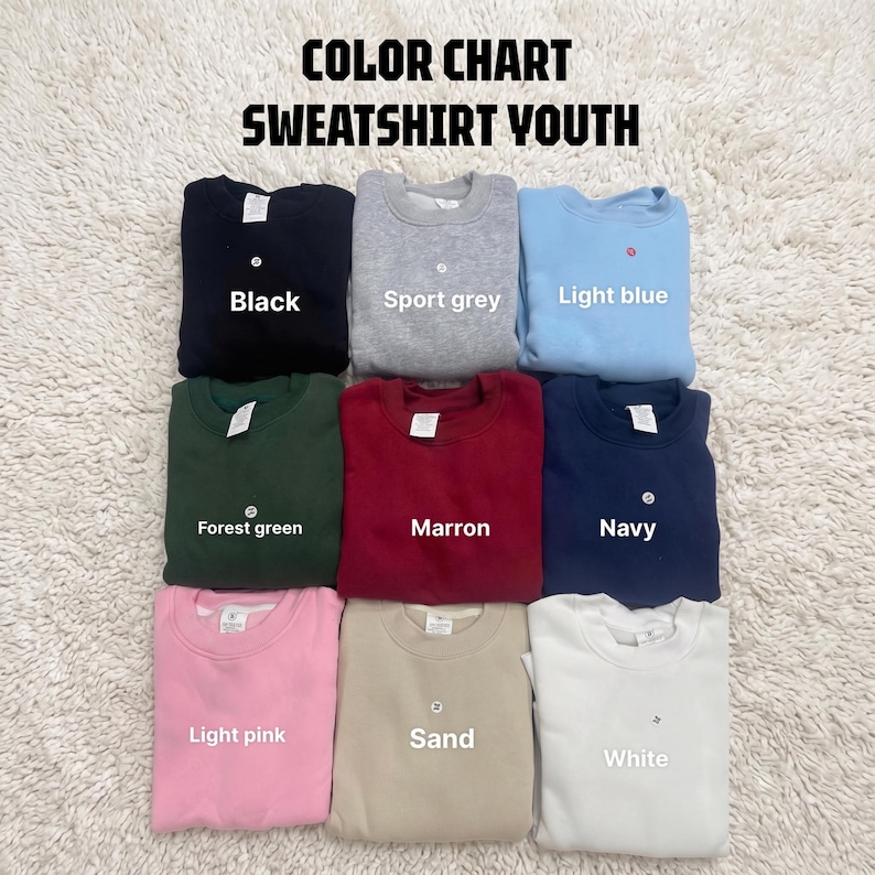 May include: A color chart for youth sweatshirts featuring nine folded crewneck sweaters in black, sport grey, light blue, forest green, maroon, navy, light pink, sand, and white. The text COLOR CHART SWEATSHIRT YOUTH is displayed at the top.