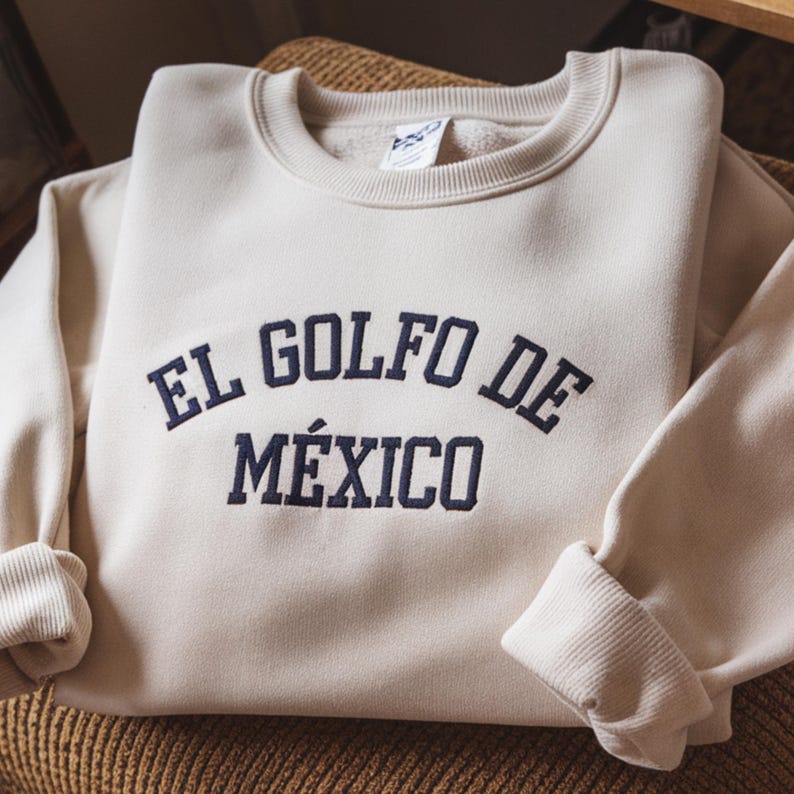 May include: A cream-colored sweatshirt with the text "EL GOLFO DE M&Eacute;XICO" embroidered in navy blue.