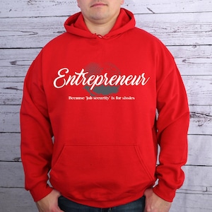 May include: Red hooded sweatshirt with the text "Entrepreneur" in white cursive lettering and the phrase "Because 'job security' is for sissies" in gray lettering.