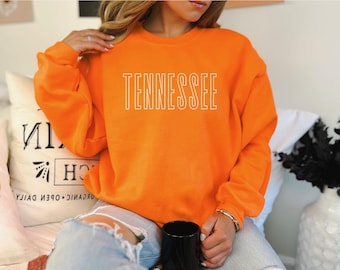 May include: A bright orange sweatshirt with the word "TENNESSEE" printed in white on the front.