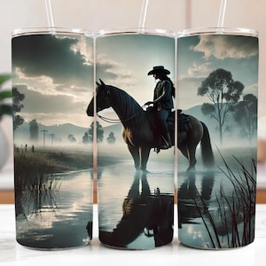 May include: A stainless steel tumbler with a design of a person riding a horse through a misty field. The tumbler has a straw and a lid.