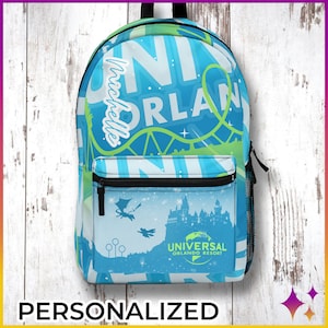 Puede incluir: Una mochila personalizada azul y verde con el texto "Universal Orlando Resort" y un gráfico del castillo de Hogwarts. La mochila también presenta una montaña rusa y el texto "Michelle".