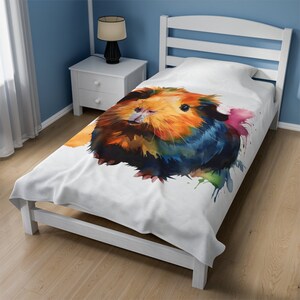 Peut inclure: Une housse de couette blanche avec une peinture à l'aquarelle d'un cochon d'Inde. Le cochon d'Inde est orange, brun et noir sur un fond blanc. La peinture a des éclaboussures de couleur autour du cochon d'Inde.