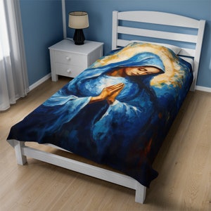 May include: A blue twin-sized bedspread with a painting of a woman in a blue robe with her hands clasped in prayer.