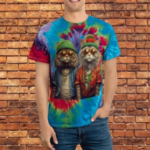 May include: A tie-dye t-shirt with a colourful design featuring two cats wearing sunglasses and hats. The cats are wearing stylish clothing and have a cool, relaxed vibe.