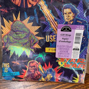 May include: Star Wars gift wrap with illustrations of characters including Jabba the Hutt, Chewbacca, and Han Solo. The design features Star Wars elements on a dark background. The package contains two sheets, each measuring 50.8 cm x 76.2 cm.