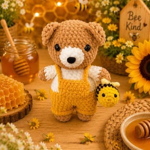 K&ouml;nnte beinhalten: Ein braun-wei&szlig;er geh&auml;kelter Teddyb&auml;r, der eine gelbe Latzhose tr&auml;gt und eine kleine geh&auml;kelte Biene h&auml;lt. Der B&auml;r hat schwarze Augen und eine schwarze Nase sowie eine weiche, strukturierte Garnoberfl&auml;che. Die Figur steht aufrecht und zeigt eine detaillierte handgefertigte Konstruktion mit rundem Kopf und Gliedma&szlig;en.