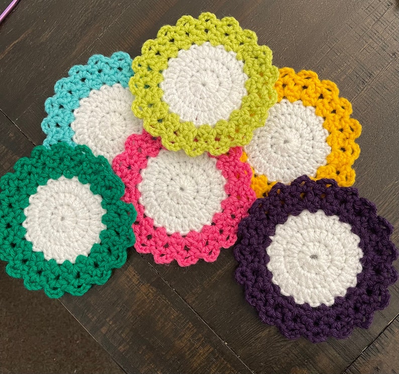 Peut inclure: Six sous-verres en crochet de diff&eacute;rentes couleurs, dont le vert, le violet, le rose, le jaune et le bleu. Chaque sous-verre a un cercle central blanc.